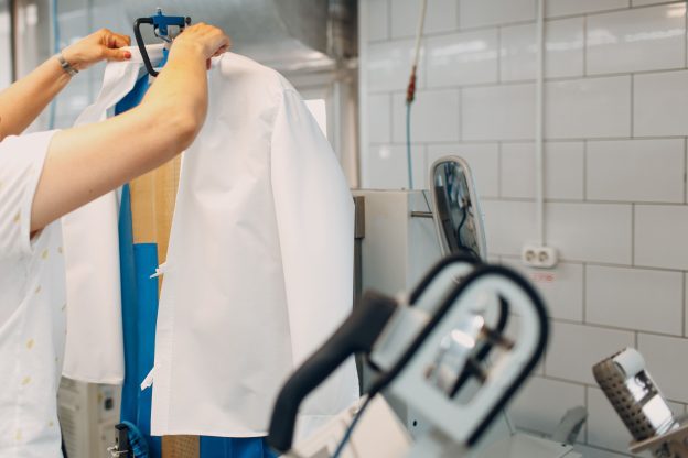 Processo de lavagem a seco sendo realizado em camisa social com equipamento profissional de lavanderia